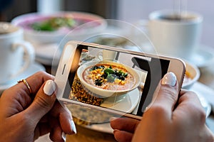 Young woman hands make photo of pumpkin and carrot soup. Take social networks smartphone food photography.