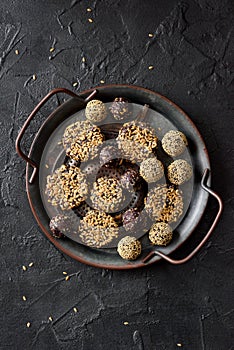 Healthy raw vegan snack. Homemade cookies and balls with flax seeds in metal tray on black background copy space