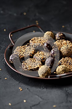Healthy raw vegan sweets. Homemade energy bites with flax seeds in metal tray on black background