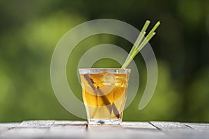 Healthy, refreshing drink of cinnamon and stalks of lemongrass on a wooden table in a tropical garden