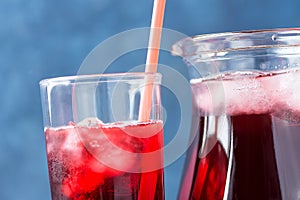 Healthy Refreshing Drink From Ice Hibiscus Tea and Red Berries and Fruits Juice in Pitcher and Tall Glass with Straw. Vitamins