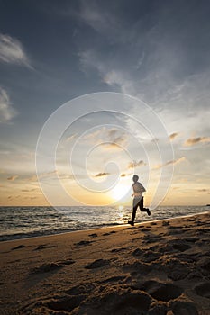 Healthy running runner man during sunset on the beach workout jog. sunflare through the mist gives atmospheric feel and depth to