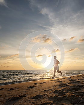 Healthy running runner man during sunset on the beach workout jog. sunflare through the mist gives atmospheric feel and depth to