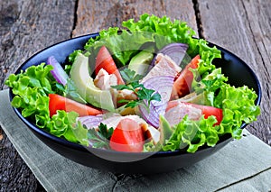 Healthy salad of avocado, tomatoes, canned tuna, onions and lettuce with parmesan, parsley and olive oil