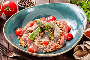 Healthy salad of barley porridge with asparagus, tomatoes and mushrooms on plate.