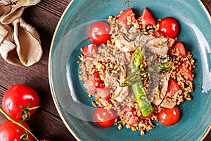Healthy salad of barley porridge with asparagus, tomatoes and mushrooms on plate. Vegan food.