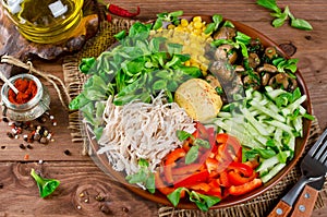 Healthy salad bowl with chicken, mushrooms, corn, cucumbers, sweet pepper and mix salad