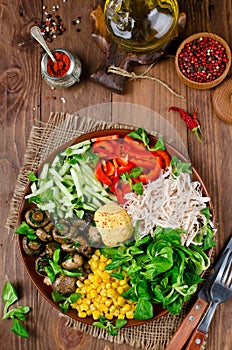 Healthy salad bowl with chicken, mushrooms, corn, cucumbers, sweet pepper and mix salad