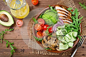 Healthy salad bowl with chicken, mushrooms, tomatoes, cucumbers, avocado and arugula