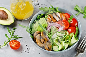 Healthy salad bowl with chicken, mushrooms, tomatoes, cucumbers, avocado and arugula