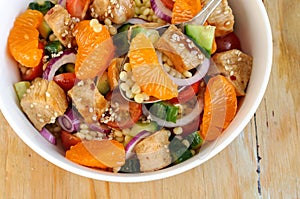 Healthy salad bowl with cuscus, chicken, tangerine and sesame seeds