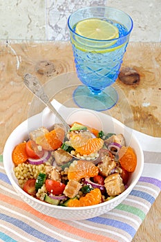 Healthy salad bowl with cuscus, chicken, tangerine and sesame seeds