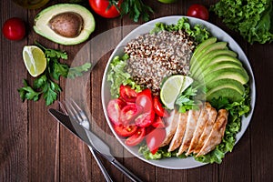 Healthy salad bowl with quinoa, tomatoes, chicken, avocado, lime and mixed greens, lettuce, parsley