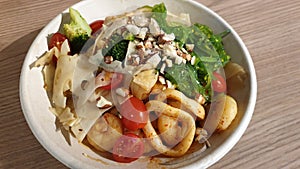 Healthy salad bowl on wooden table close up view