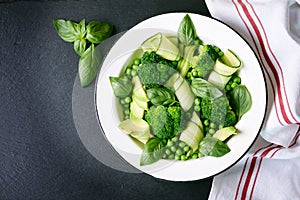 Healthy salad of broccoli, green peas, cucumber and avocado with basil and olive oil. Healthy food. Top view, copy space.