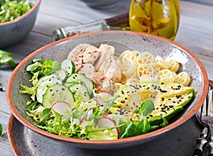 Healthy salad with chicken, avocado, cucumber, lettuce, radish and pasta on dark background. Proper nutrition. Dietary menu.