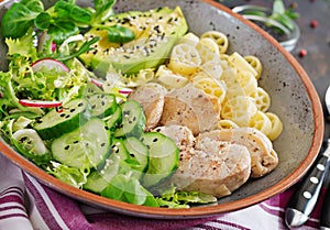 Healthy salad with chicken, avocado, cucumber, lettuce, radish and pasta on dark background. Proper nutrition. Dietary menu.