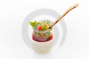 Healthy salad with cream cheese, jam and toasted seed bread stick plated in glass yogurt jar on a white background