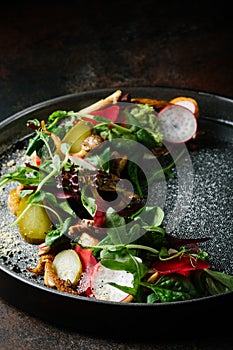 Healthy salad of fresh vegetables - tomatoes, avocado, arugula, radish and seeds on a bowl. Vegan food. Close up
