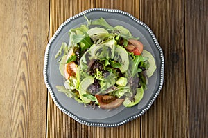 Healthy salad mix of iceberg, spinach, avocado and cucumber with olive oil, tomato and lemon. Top view