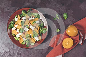 Healthy salad with persimmon, doucette lambs-lettuce, cornsalad, feld salad and feta cheese. Fitness food. Superfoods Vitamin