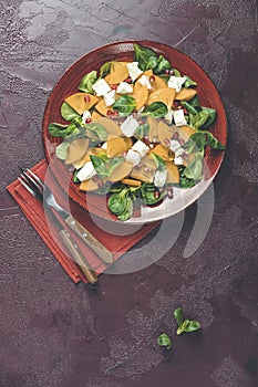 Healthy salad with persimmon, doucette lambs-lettuce, cornsalad, feld salad and feta cheese. Fitness food. Superfoods Vitamin