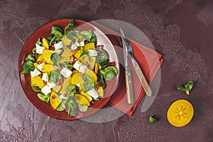 Healthy salad with persimmon, doucette lambs-lettuce, cornsalad, feld salad and feta cheese. Fitness food, superfoods vitamin