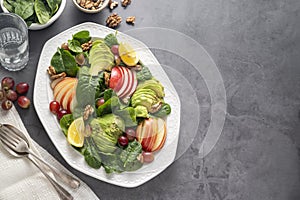 Healthy salad with red apple, wallnuts, grapes and fresh spinach leaves. Copy space, top view