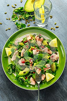 Healthy Salmon, Avocado salad with watercress and goji berries, pumpkin seed mix on green plate