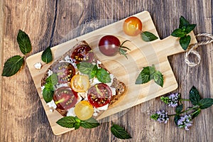 Healthy sandwich with cheese, mint, cherry tomatoes,  black bread on wooden table