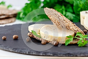 Healthy sandwich with homemade dietary chicken sausage and multi-loaf bread on slate board.