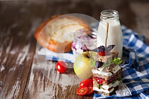 Healthy school lunch with a sandwich, fresh fruits, bun and milk