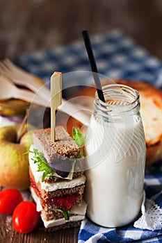 Healthy school lunch with a sandwich, fresh fruits, bun and milk