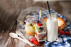 Healthy school lunch with a sandwich, fresh fruits, bun and milk