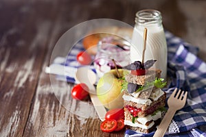 Healthy school lunch with a sandwich, fresh fruits, bun and milk