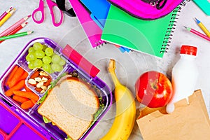 Healthy school lunch with school supplies on a white marble background