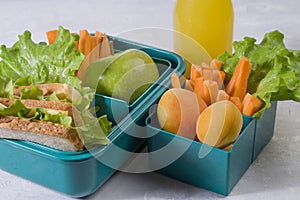 Healthy school lunch with virus protection. Lunch box with a sandwich, fresh vegetables and fruits, a bottle of juice on a light