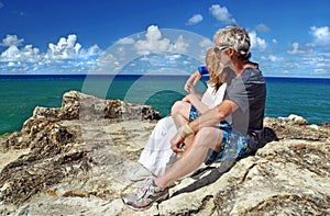 Healthy senior couple resting after hiking to cliff top tropical island