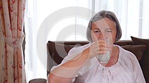 Healthy senior lady drinking a glass of fresh milk