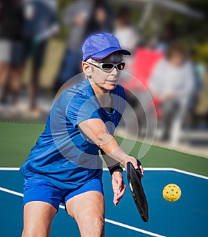 Healthy senior woman athlete hits a Pickleball volley close to the net photo