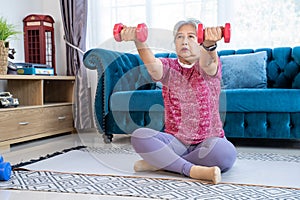 Healthy senior woman doing exercise with dumbbells at home