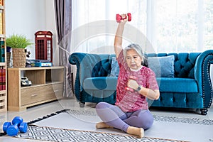 Healthy senior woman doing exercise with dumbbells at home