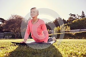 Healthy senior woman in a yoga pose with gentle sunflare