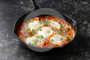 Healthy shakshuka with vegetables, herbs, tomatoes in iron cast pan