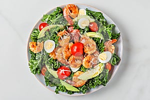 Healthy shrimp caesar salad with avocado, parmesan cheese, tomatoes and kale on white background. top view
