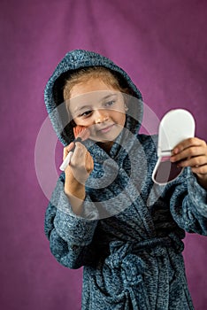 healthy skin of a beautiful little girl looking in the mirror and touching her face.