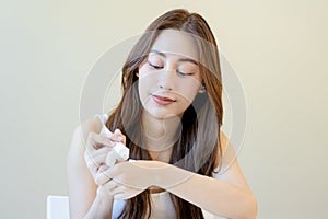 Healthy skin care, smile asian young woman squeeze out cream from tube on her back hand before applying moisturizer, putting cream
