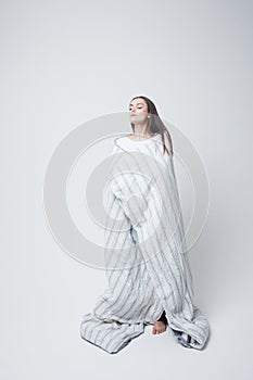 Healthy sleep and drowsiness, beautiful young woman standing wrapped in a blanket