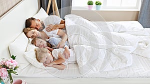 Healthy sleep. happy family parents and children sleeping in white bed