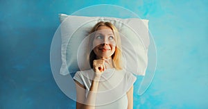 Healthy sleep, happy relaxed sleepy young woman on white soft comfortable pillow thinking looks away imagining she lying on the